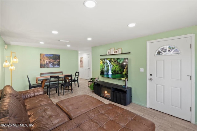 living area featuring recessed lighting, wood finished floors, visible vents, and a lit fireplace