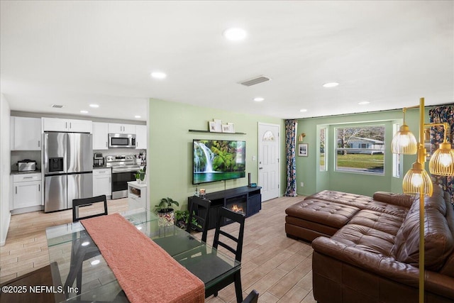 living room featuring recessed lighting, visible vents, and light wood-style floors