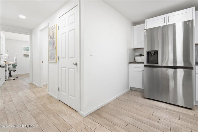 kitchen with baseboards, wood tiled floor, stainless steel fridge with ice dispenser, recessed lighting, and white cabinetry