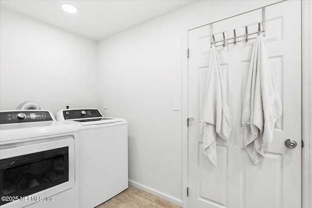 clothes washing area featuring laundry area, washing machine and dryer, light wood-type flooring, and baseboards