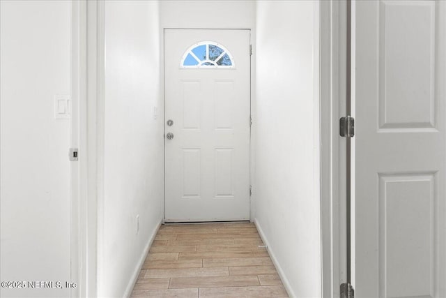 doorway to outside with baseboards and wood finish floors