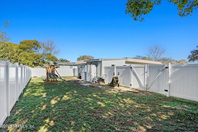 view of yard featuring a playground, a fenced backyard, and a gate