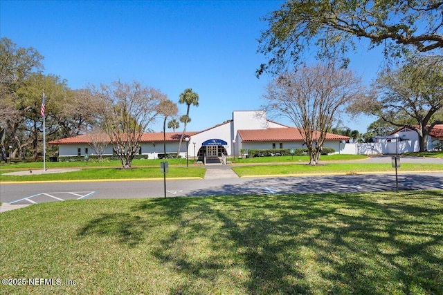 view of front of property featuring a front lawn, a tile roof, and stucco siding