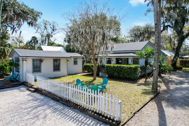 back of property featuring a fenced front yard and a lawn