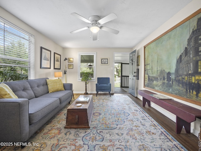 living area featuring baseboards, plenty of natural light, a ceiling fan, and wood finished floors