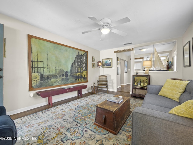 living area with baseboards, visible vents, ceiling fan, and wood finished floors