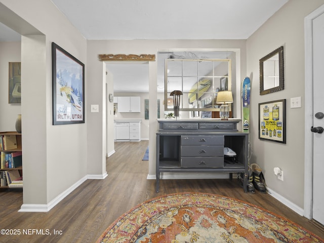 corridor with dark wood-style flooring and baseboards