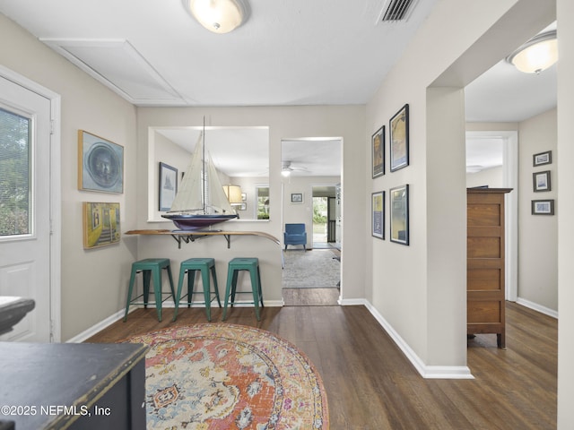 interior space with a breakfast bar, visible vents, baseboards, and wood finished floors