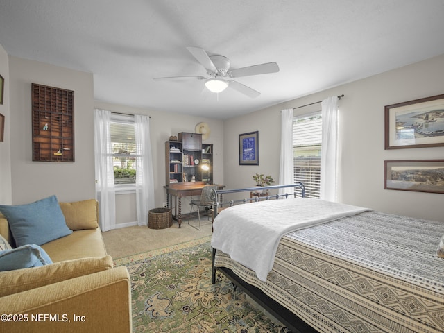 carpeted bedroom with ceiling fan, multiple windows, and baseboards