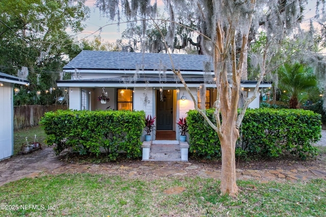 view of front of home featuring fence and roof with shingles