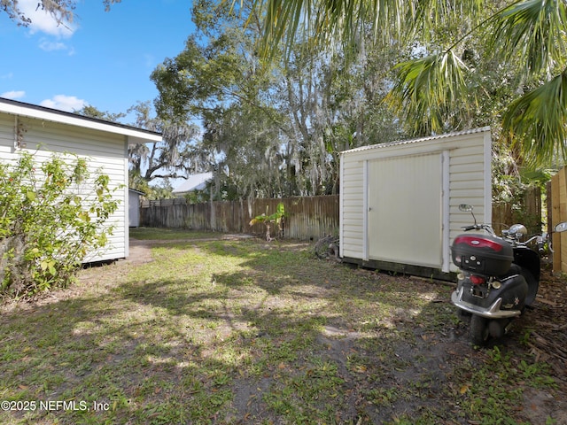 view of yard with an outdoor structure, fence, and a storage shed