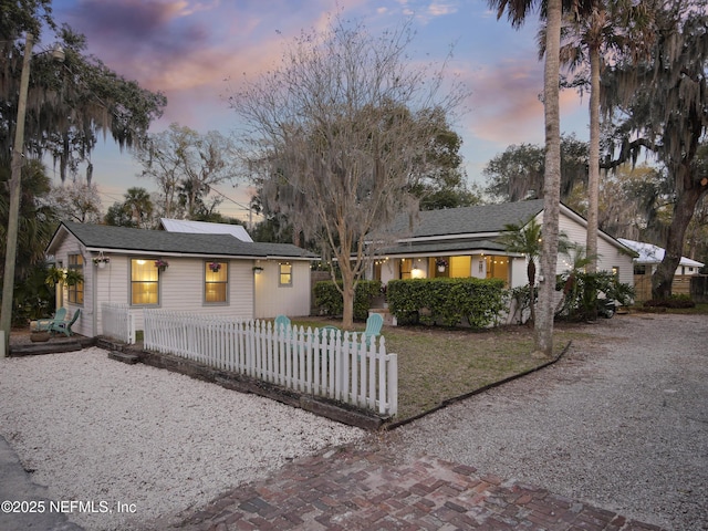 ranch-style home featuring a fenced front yard and roof mounted solar panels