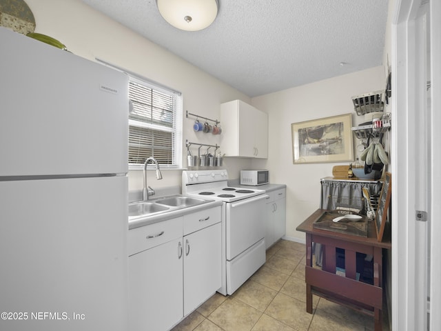 kitchen with white appliances, white cabinets, a sink, and light tile patterned floors