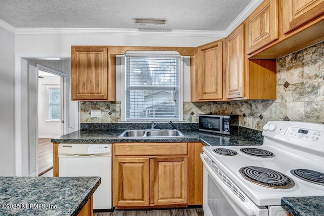 kitchen with a textured ceiling, white appliances, a sink, decorative backsplash, and dark countertops