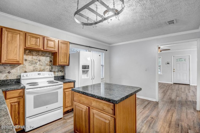 kitchen with dark countertops, white appliances, visible vents, and light wood-style floors