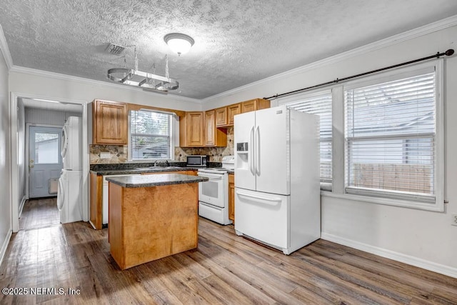 kitchen with white appliances, a kitchen island, wood finished floors, crown molding, and a sink