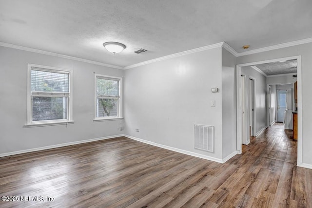 spare room with baseboards, crown molding, visible vents, and wood finished floors