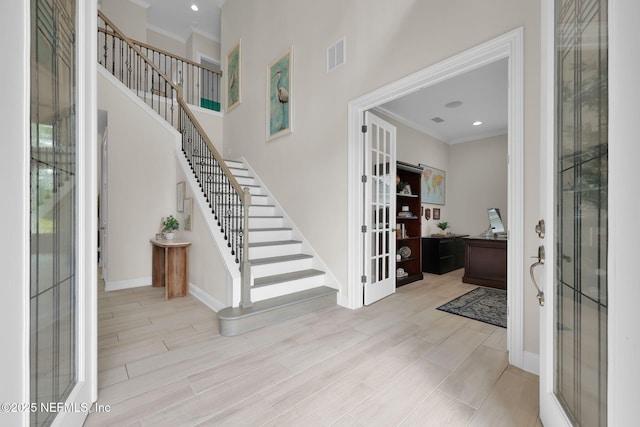 foyer entrance featuring stairs, visible vents, crown molding, and wood finish floors