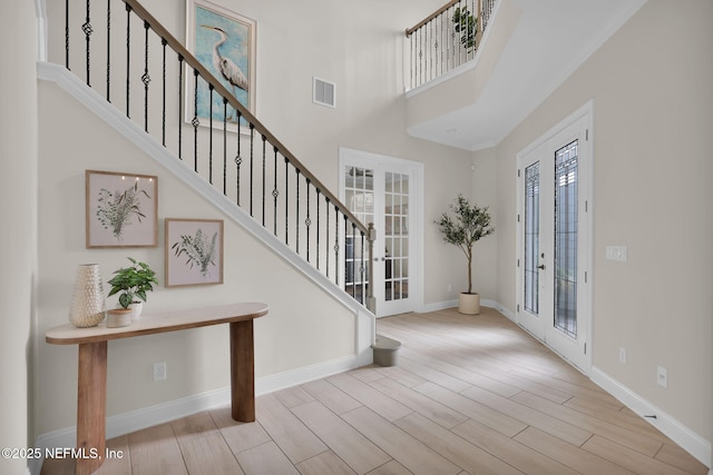 foyer entrance featuring french doors, visible vents, stairway, and wood finished floors