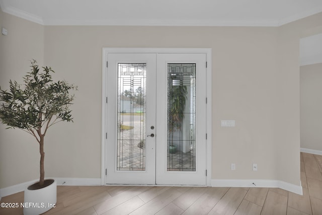 entryway featuring light wood-style flooring, baseboards, crown molding, and french doors