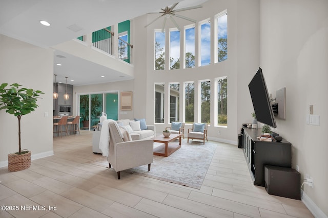 living room featuring a high ceiling, recessed lighting, and baseboards