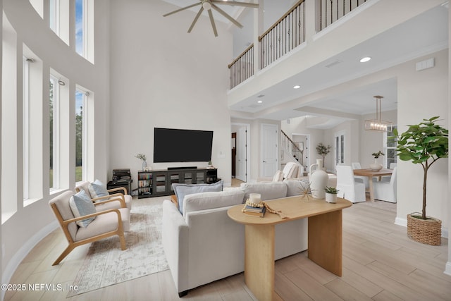 living room featuring a healthy amount of sunlight, stairway, light wood-type flooring, and baseboards