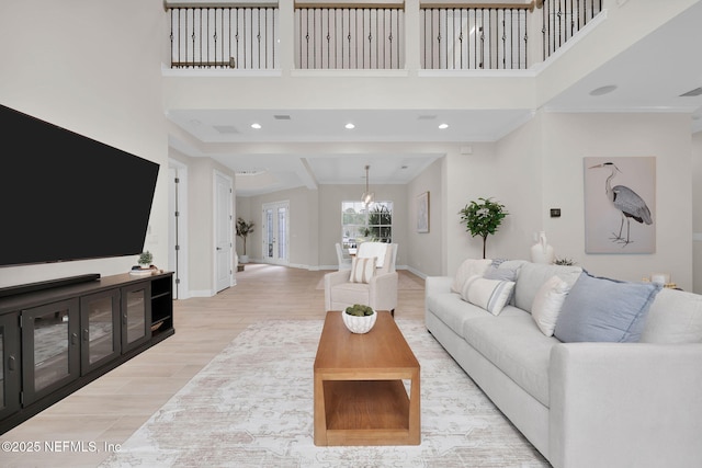 living area featuring recessed lighting, a high ceiling, wood finished floors, a chandelier, and baseboards