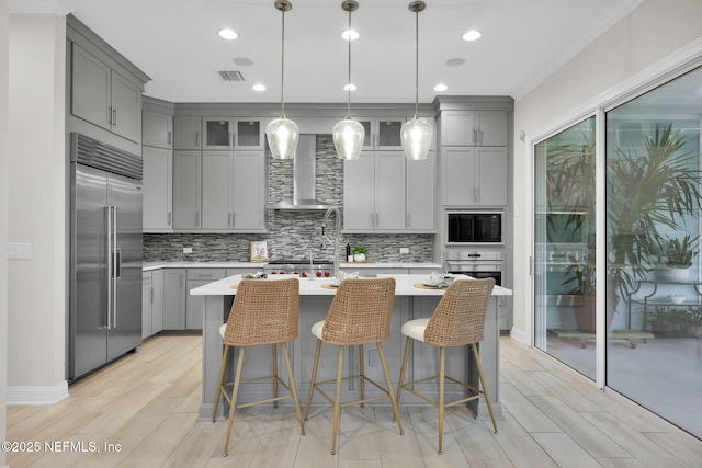 kitchen featuring wall chimney exhaust hood, appliances with stainless steel finishes, and gray cabinetry