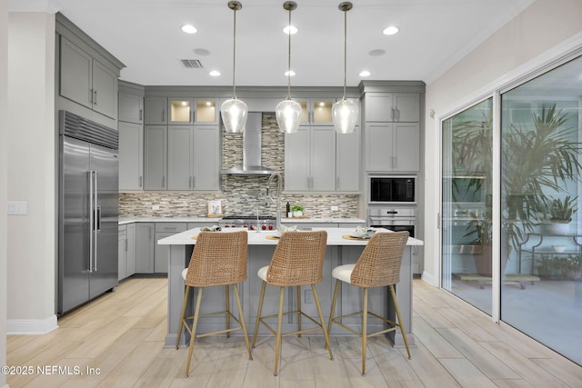 kitchen featuring wall chimney exhaust hood, appliances with stainless steel finishes, light countertops, and gray cabinetry