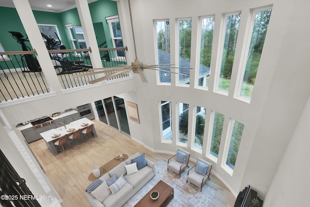 living area featuring stairs, wood finished floors, a towering ceiling, and baseboards