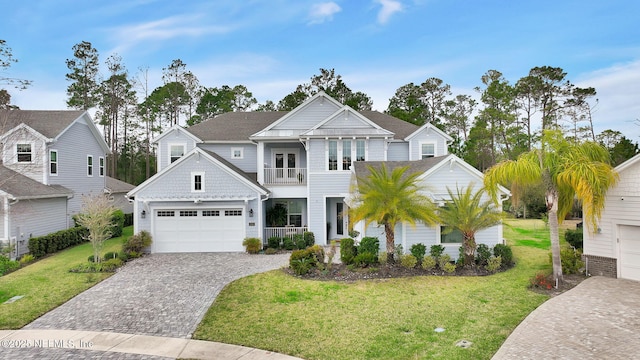 view of front of home with a balcony, decorative driveway, and a front yard