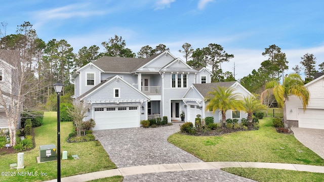 view of front of property featuring a balcony, roof with shingles, decorative driveway, and a front yard