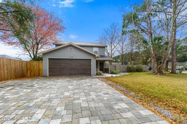 view of front of house with an attached garage, fence, a front lawn, and decorative driveway