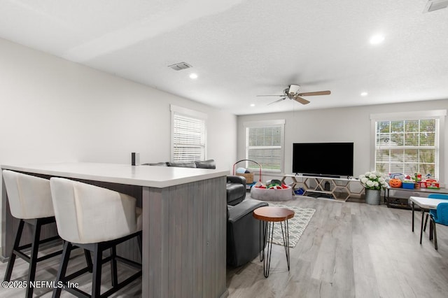 interior space featuring light wood-type flooring, visible vents, a kitchen breakfast bar, and recessed lighting