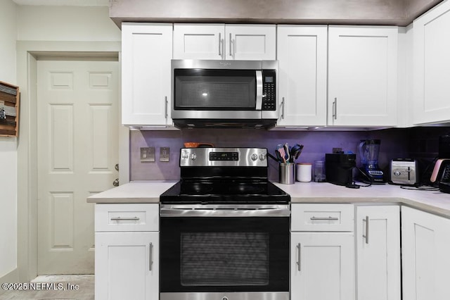 kitchen with stainless steel appliances, light countertops, and white cabinets