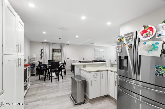 kitchen with stainless steel fridge, white cabinets, a peninsula, light countertops, and recessed lighting