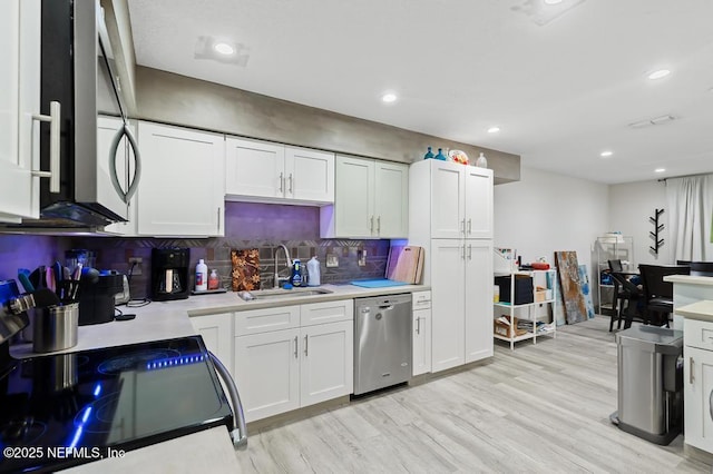 kitchen featuring light countertops, stainless steel dishwasher, a sink, and white cabinets