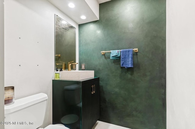 bathroom with toilet, vanity, and recessed lighting