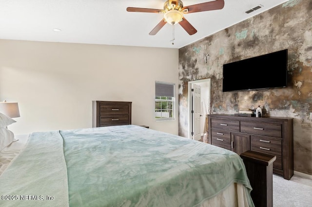 bedroom featuring an accent wall, visible vents, ceiling fan, and light carpet