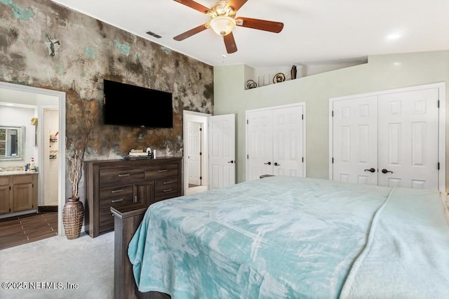 bedroom with carpet, multiple closets, lofted ceiling, a ceiling fan, and ensuite bath