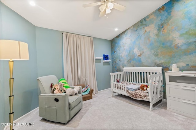 carpeted bedroom featuring a nursery area, ceiling fan, baseboards, and wallpapered walls