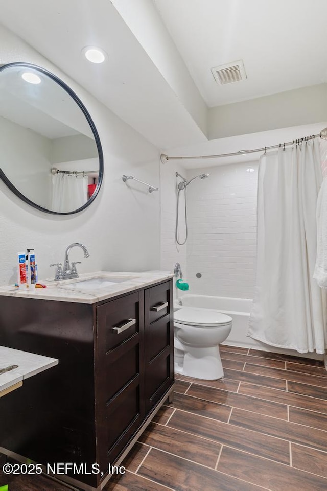 bathroom with toilet, wood finish floors, vanity, visible vents, and shower / tub combo with curtain