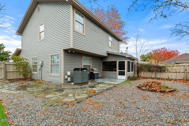 rear view of house with a patio area, a sunroom, a fenced backyard, and central air condition unit