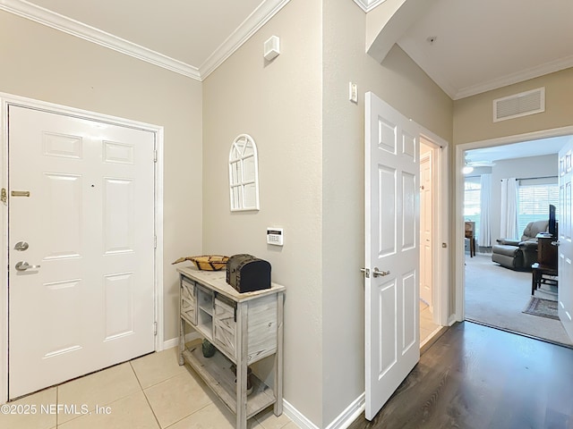 foyer with ornamental molding, visible vents, baseboards, and light tile patterned floors