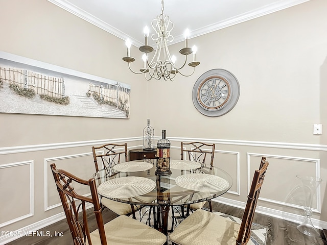 dining area with a wainscoted wall, ornamental molding, wood finished floors, a chandelier, and a decorative wall