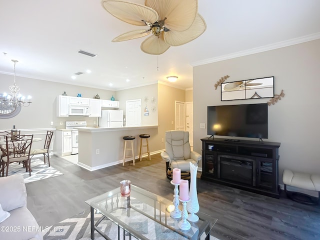 living room with baseboards, visible vents, ornamental molding, wood finished floors, and ceiling fan with notable chandelier