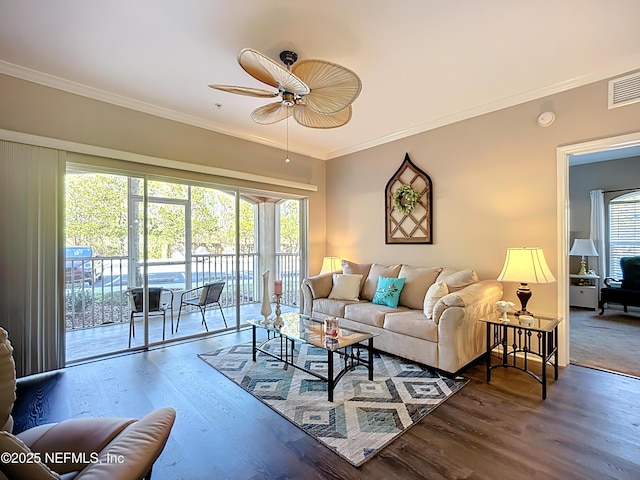 living room featuring plenty of natural light, visible vents, crown molding, and wood finished floors