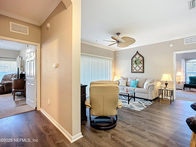 living room with wood finished floors, visible vents, and crown molding