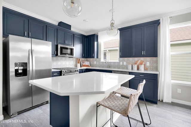 kitchen featuring appliances with stainless steel finishes, light countertops, blue cabinets, and a breakfast bar area