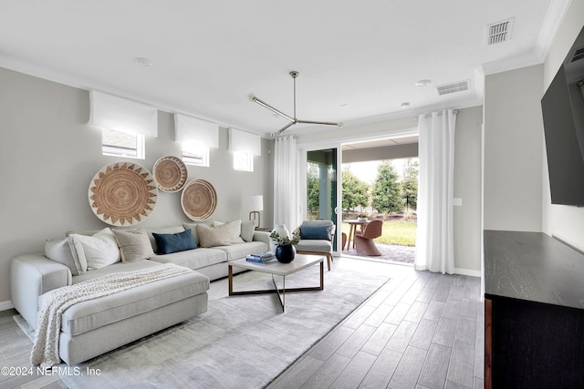 living room with baseboards, wood finished floors, visible vents, and crown molding